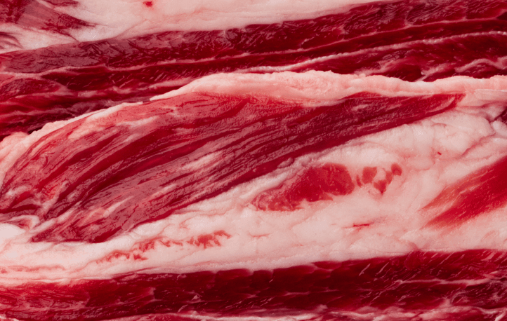 Close-up of fresh, marbled raw beef with vibrant red meat and white fat striations, showing the high-quality muscle meat used in our premium raw dog food formulations